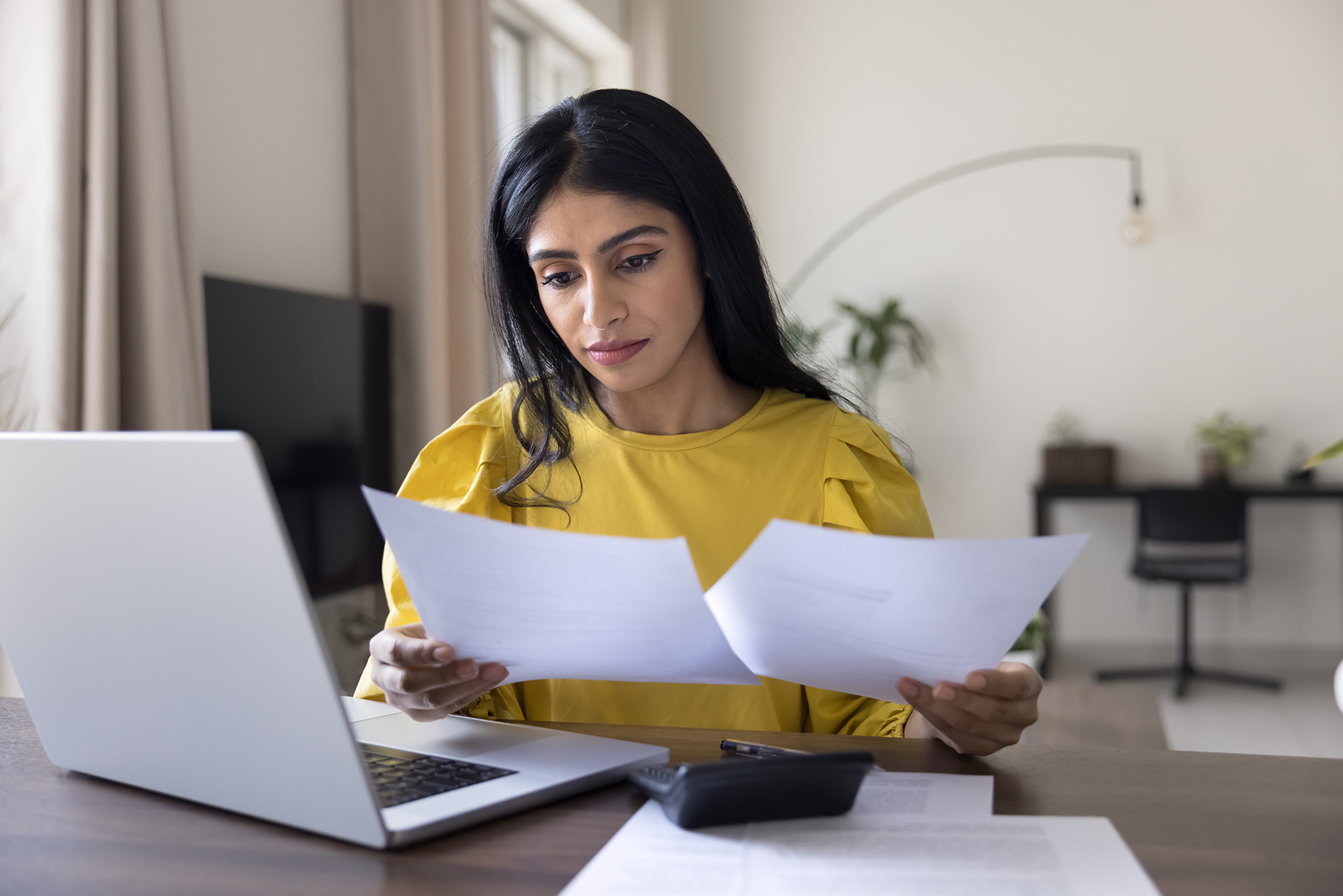Woman engaged in financial work, reviewing documents, checking papers